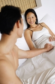 Couple in bed, man holding womans hand - Asia Images Group