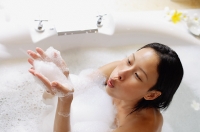 Woman in bathtub, blowing soap suds - Asia Images Group