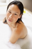 Woman in bathtub, covered with soap suds, smiling - Asia Images Group