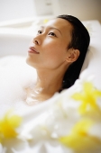 Woman in bathtub, taking bubble bath, looking away - Asia Images Group