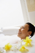 Woman in bathtub, smiling, looking away - Asia Images Group