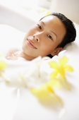 Woman in bathtub, taking bubble bath, looking at camera - Asia Images Group