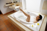 Woman in bathroom, taking at bath, washing leg, high angle view - Asia Images Group