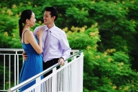 Couple standing on balcony, embracing, face to face - Asia Images Group