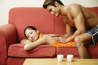 Woman lying on sofa, man giving her massage - Asia Images Group