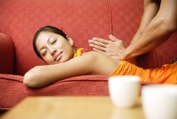 Woman lying on sofa, having her back massaged - Asia Images Group