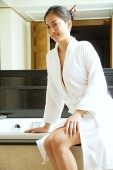 Woman in robe, sitting next to bath tub, looking at camera - Asia Images Group