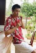 Man standing at bar counter, drinking - Asia Images Group