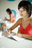 Young woman in cafe, writing in notebook - Asia Images Group