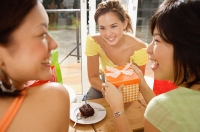 Young women at home, one holding gift - Asia Images Group