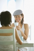 Young women in cafe, sitting face to face, having coffee - Asia Images Group
