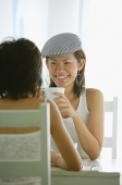 Young women in cafe, having coffee, sitting face to face - Asia Images Group