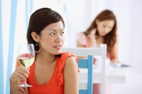 Woman in cafe, holding wine glass, looking away - Asia Images Group