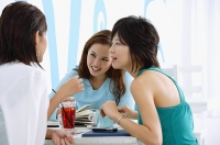 Three young women sitting in cafe, talking - Asia Images Group