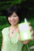 Young woman listening to mp3 player, holding it out to camera, selective focus - Asia Images Group