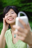 Young woman with mp3 player, eyes closed, smiling - Asia Images Group