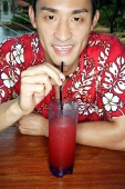 Man wearing floral shirt, having a drink, looking at camera - Asia Images Group