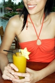 Woman sitting at bar counter, holding drink - Asia Images Group