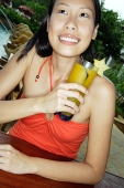 Woman sitting at bar counter, holding drink, smiling - Asia Images Group