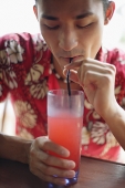 Man in floral shirt, drinking cocktail - Asia Images Group