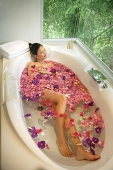 Woman in bathtub, flowers floating in water - Asia Images Group