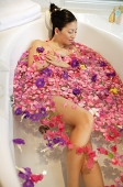 Woman in bathtub, surrounded by flowers - Asia Images Group