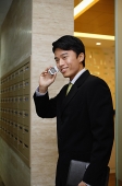 Businessman using mobile phone, smiling - Asia Images Group