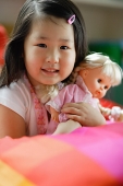 Girl holding a doll, looking at camera - Asia Images Group