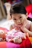 Young girl with doll, hand on chin, looking at camera - Asia Images Group