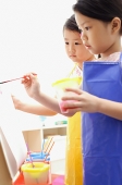Young girls painting on easel - Asia Images Group