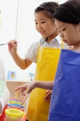 Two young girls painting on easel - Asia Images Group