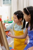 Two girls painting on easel - Asia Images Group