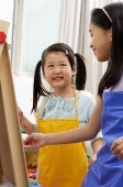 Two girls painting on easel - Asia Images Group