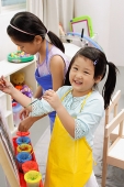 Two girls painting on easel, smiling - Asia Images Group