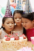 Three girls celebrating a birthday, blowing birthday candles - Asia Images Group