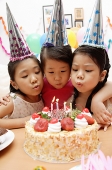 Three girls blowing candles on birthday cake - Asia Images Group