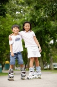 Children on rollerblades, arms around each other - Asia Images Group