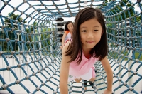 Girls at playground, going through net tunnel - Asia Images Group