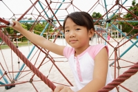 Girl on jungle gym, looking at camera - Asia Images Group