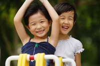 Two girls on a seesaw, smiling - Asia Images Group