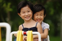 Two girls on a seesaw, smiling, portrait - Asia Images Group