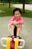 Young girl on seesaw, smiling at camera - Asia Images Group