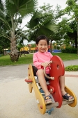 Young girl sitting on playground hobby horse - Asia Images Group