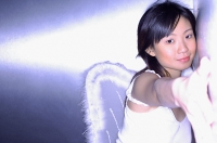 Young woman wearing angel wings, hugging wall, looking at camera - Asia Images Group
