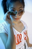 Young woman adjusting sunglasses, looking at camera - Asia Images Group