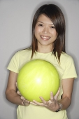 Woman holding yellow bowling ball, smiling at camera - Asia Images Group
