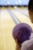 Woman holding bowling ball, over the shoulder view - Asia Images Group