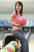 Woman at bowling alley holding bowling ball - Asia Images Group