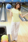 Woman holding bowling ball, standing at bowling alley - Asia Images Group