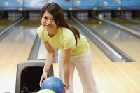 Woman selecting bowling ball, smiling at camera - Asia Images Group